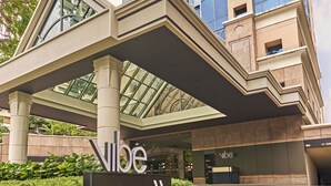 A modern hotel entrance with a glass facade, a covered walkway, and a sign indicating the name "Nibe." - Vibe Hotel Singapore Orchard (Singapore)