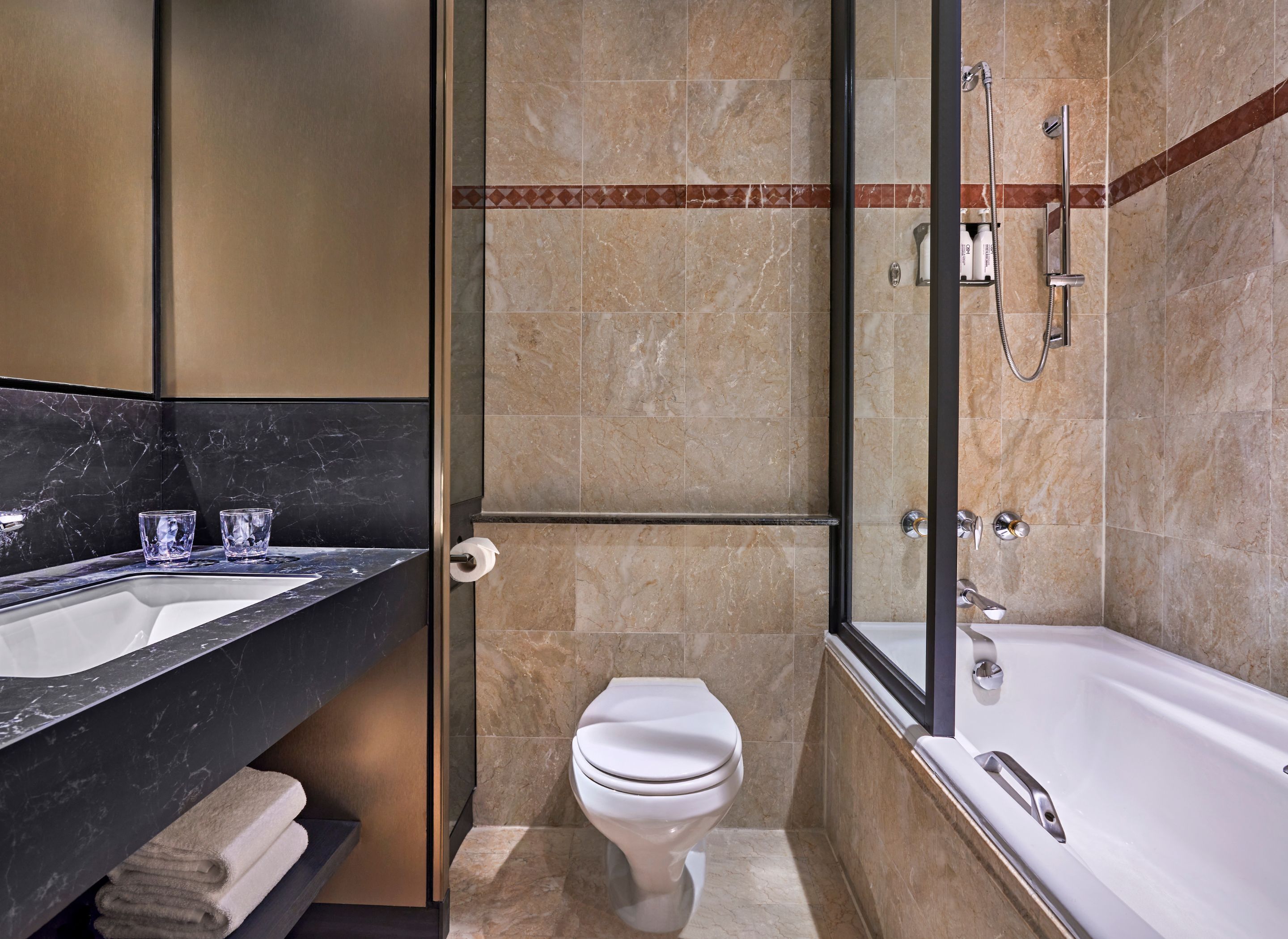 A modern bathroom with a glass-enclosed shower, a white toilet, and a large bathtub.