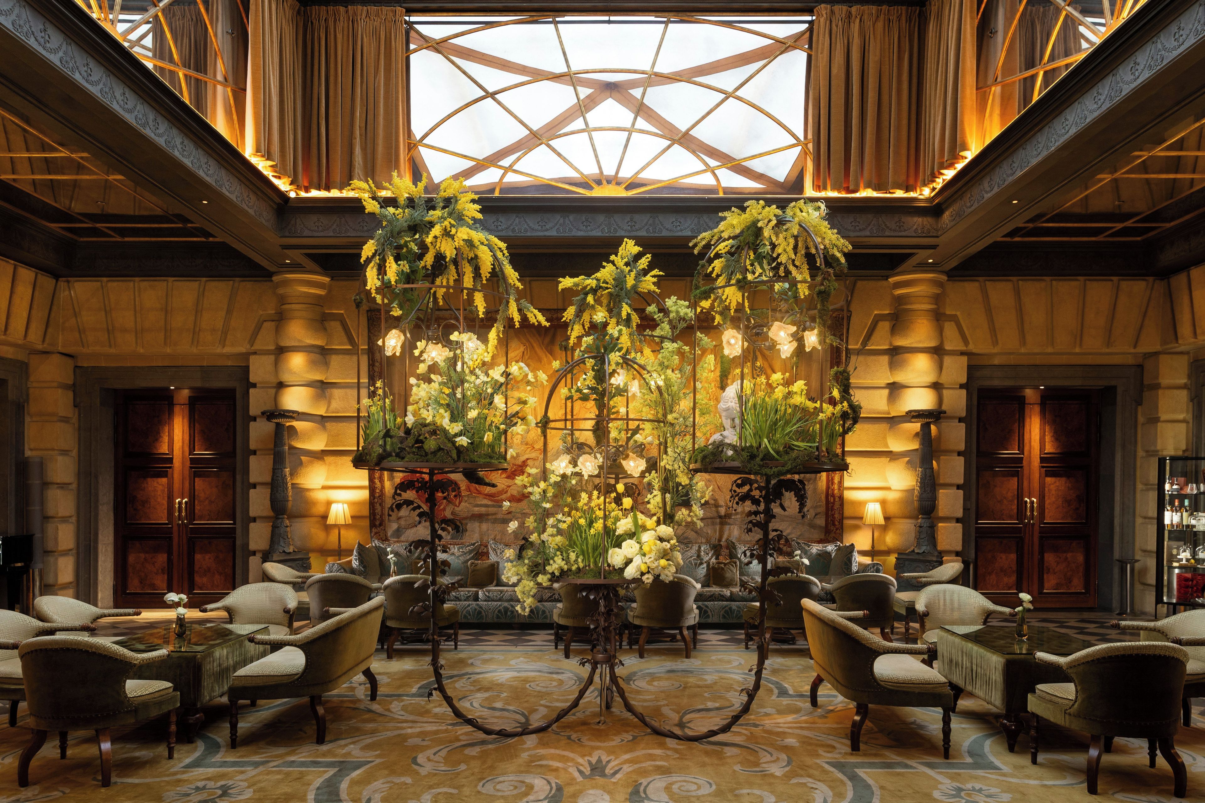 Un hall d’entrée avec un plafond haut, des lustres richement décorés et un tapis à motifs.