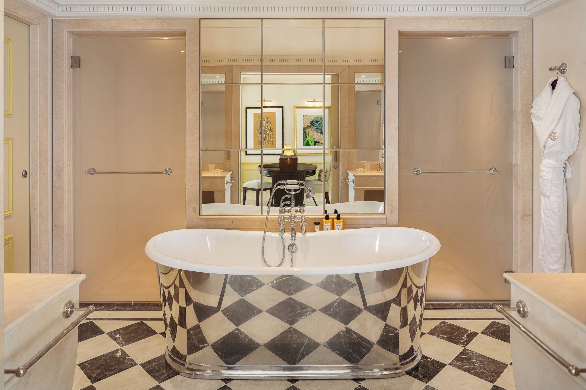 A luxurious bathroom with a freestanding bathtub, a large mirror, and a checkered floor.