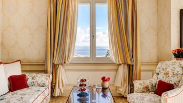 A room with a sofa, armchair, and a table with a dessert display and glasses.