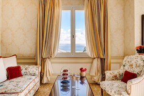 A room with a sofa, armchair, and a table with a dessert display and glasses.