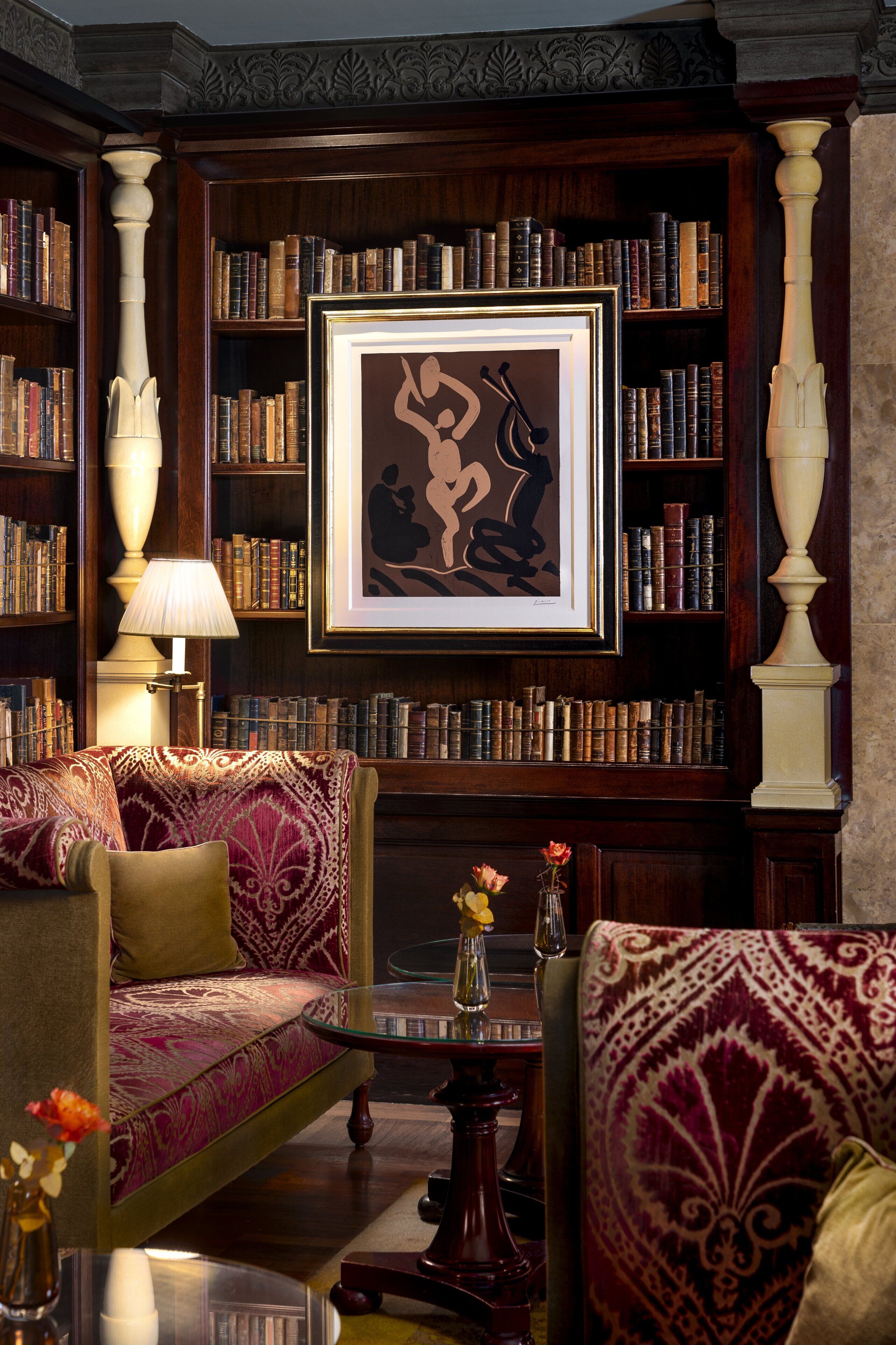 A library with bookshelves, a framed artwork, and a sofa.