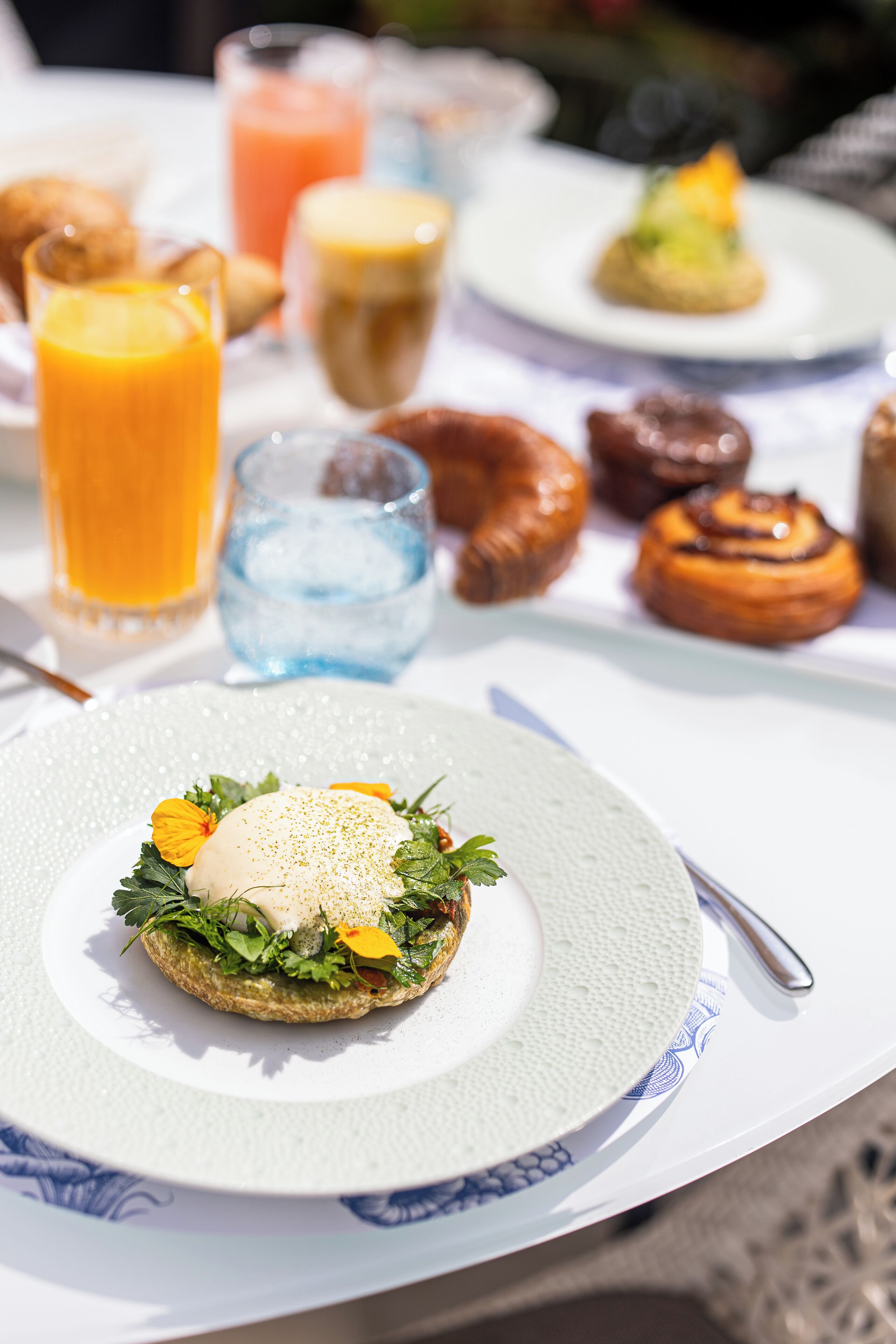 Une table mise pour le petit-déjeuner, avec une assiette de nourriture, un verre de jus d’orange et un verre d’eau.
