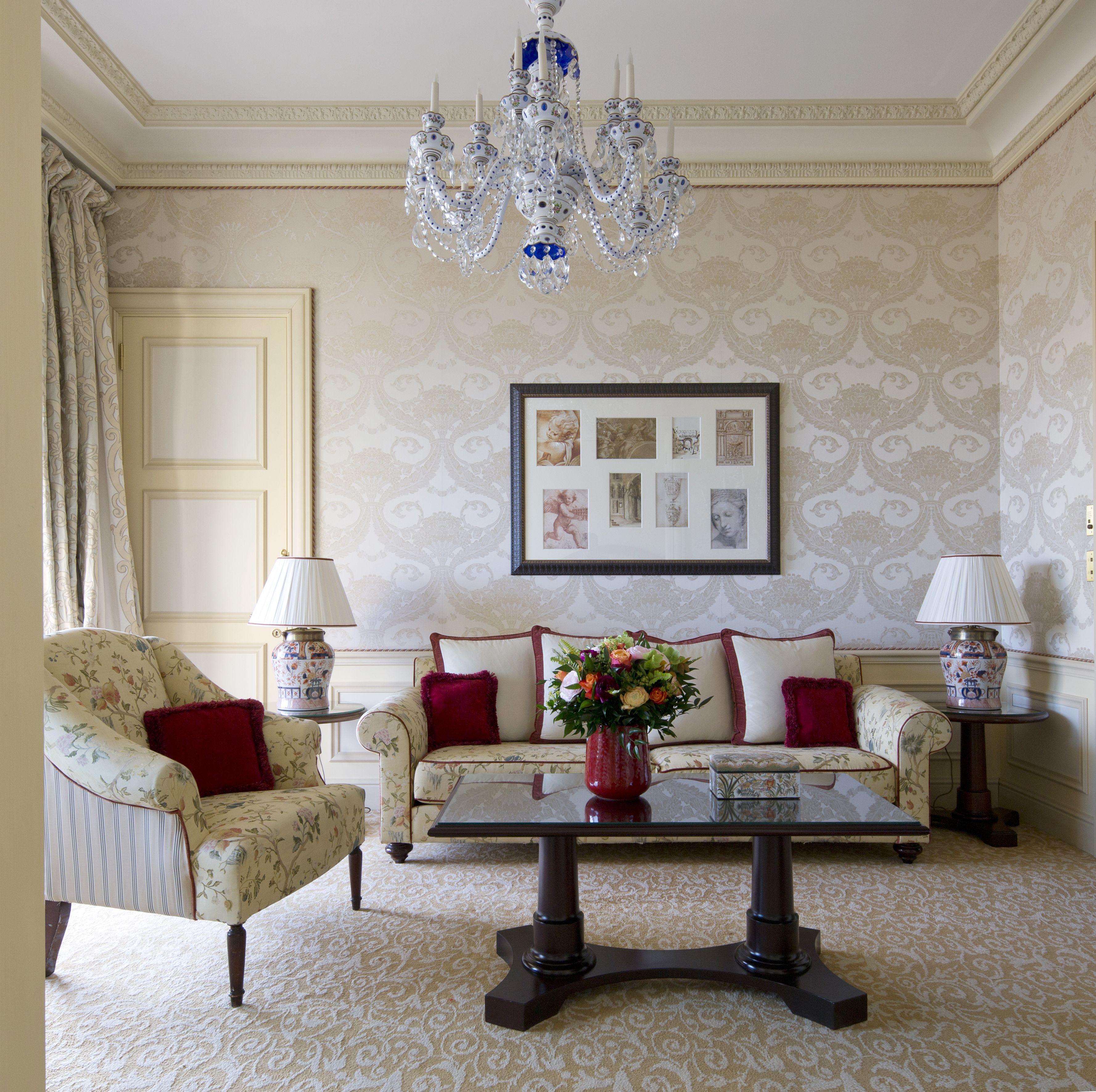 Una habitación con sofá, una mesa de centro, un candelabro y cuadros enmarcados en la pared.