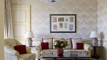 Una habitación con sofá, una mesa de centro, un candelabro y cuadros enmarcados en la pared.