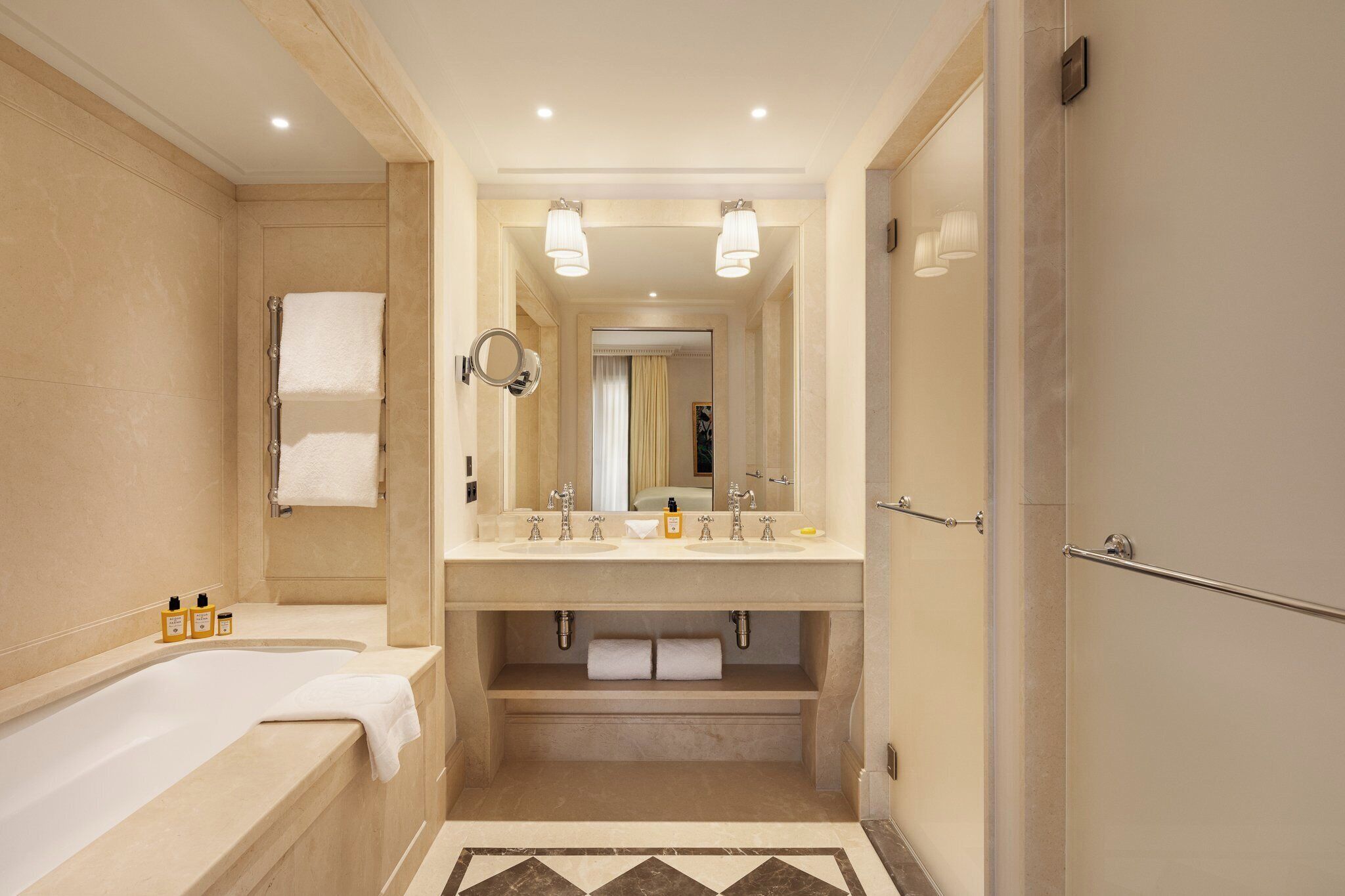 A modern bathroom with a bathtub, double sink vanity, and a large mirror.