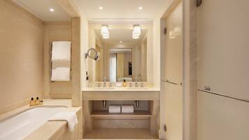 A modern bathroom with a bathtub, double sink vanity, and a large mirror.