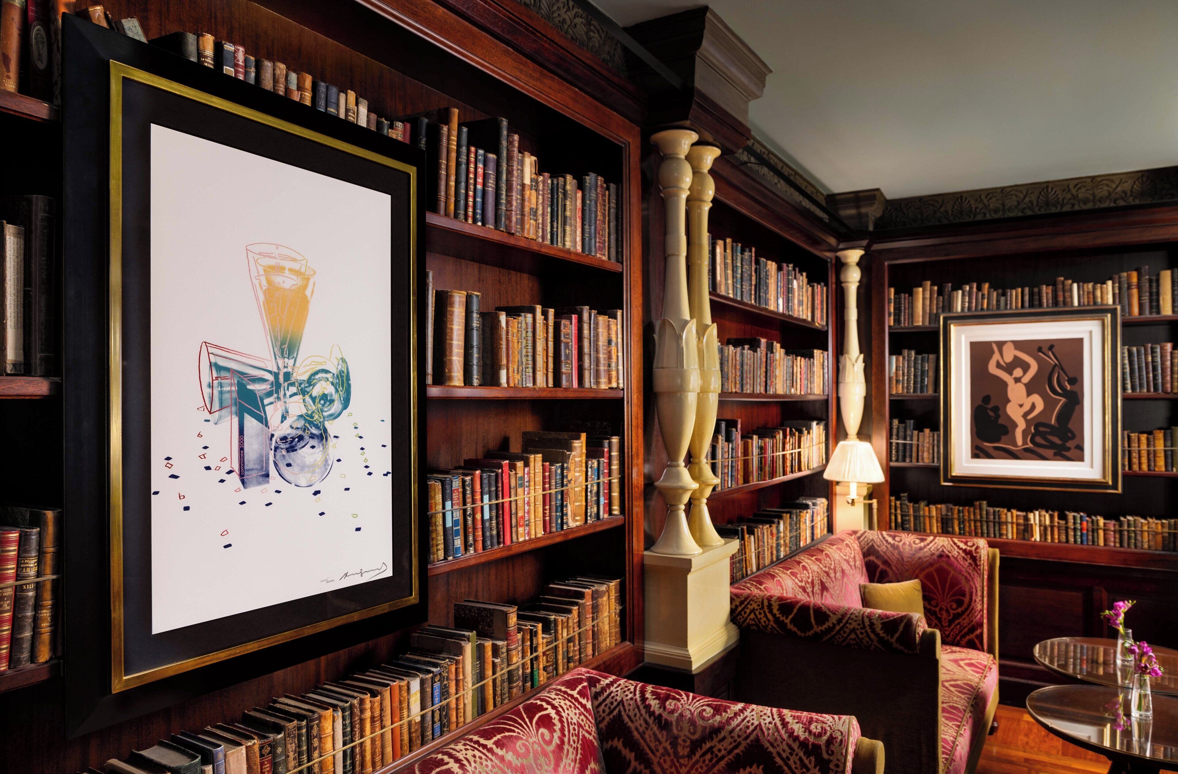 A library with bookshelves, a framed artwork, and a patterned sofa.