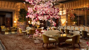 A luxurious hotel lobby with plush seating, elegant decor, and a large mirror reflecting the space.