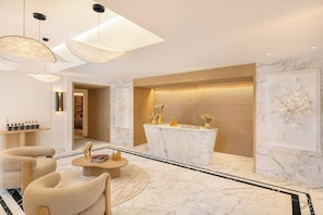 A modern lobby with a marble reception desk, comfortable seating, and contemporary lighting fixtures.