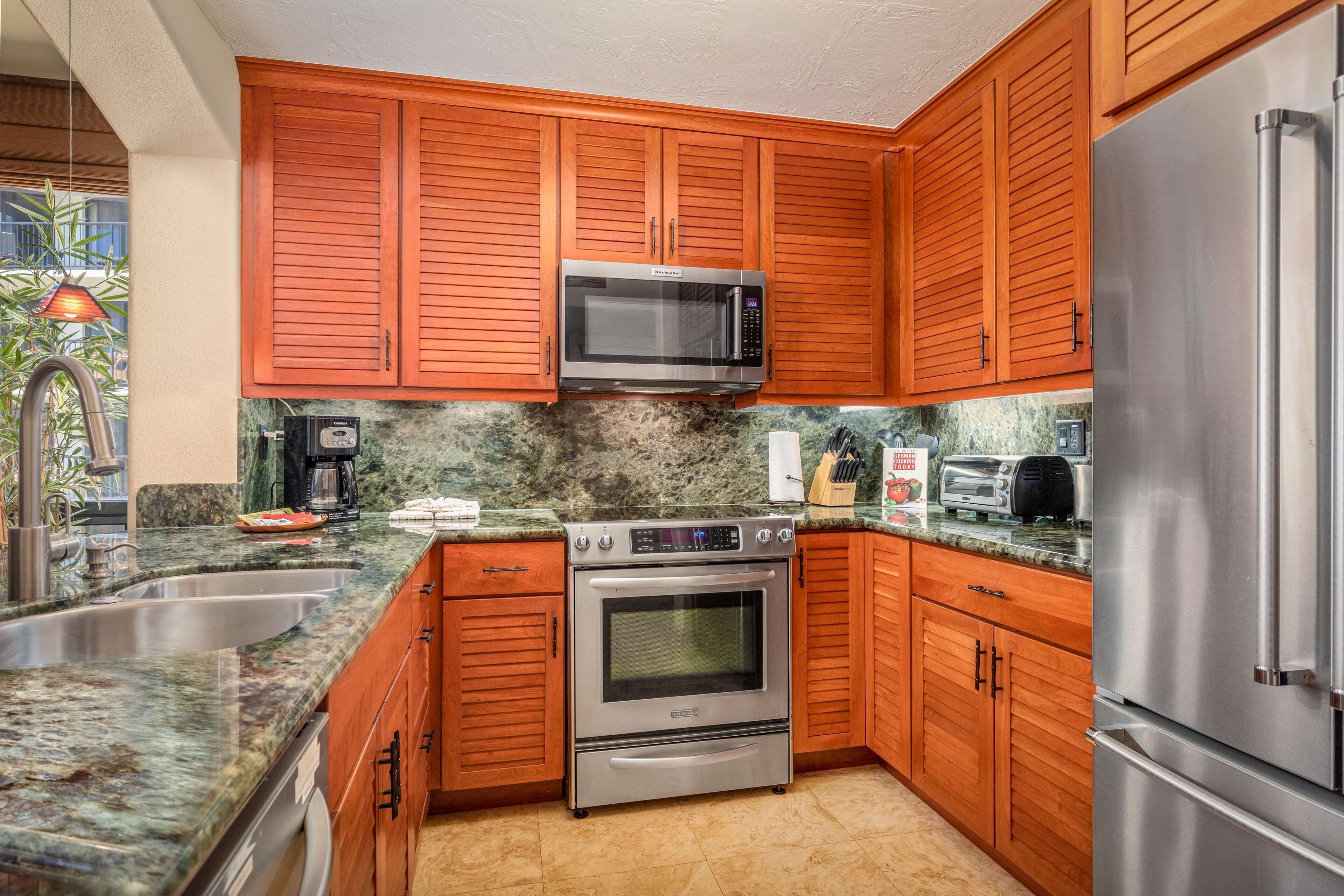 Una cocina con gabinetes de madera, electrodomésticos de acero inoxidable, encimeras de granito y horno empotrado.