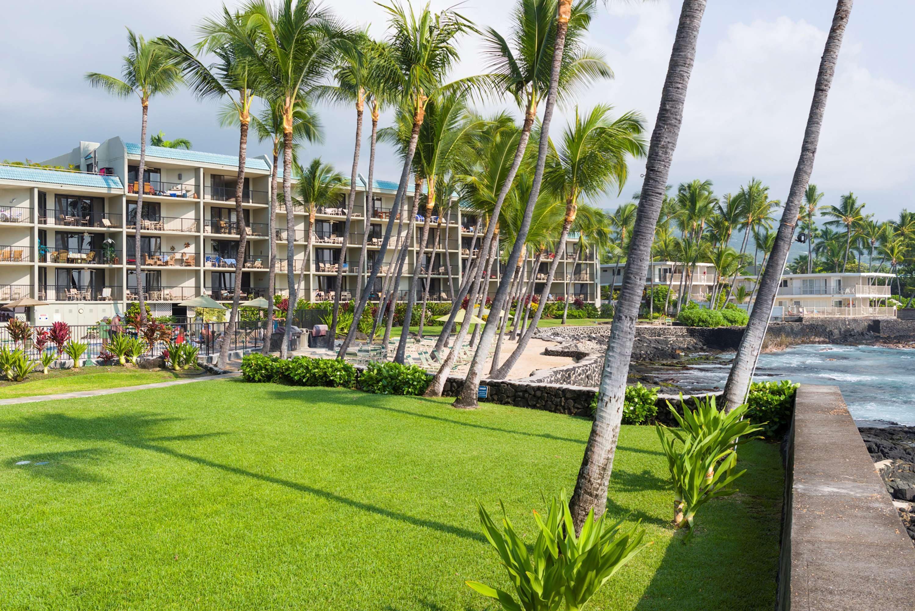 A hotel with multiple floors, a pool area, and palm trees.
