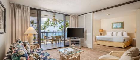 Una habitación de hotel con balcón, sofá, cama y televisor.