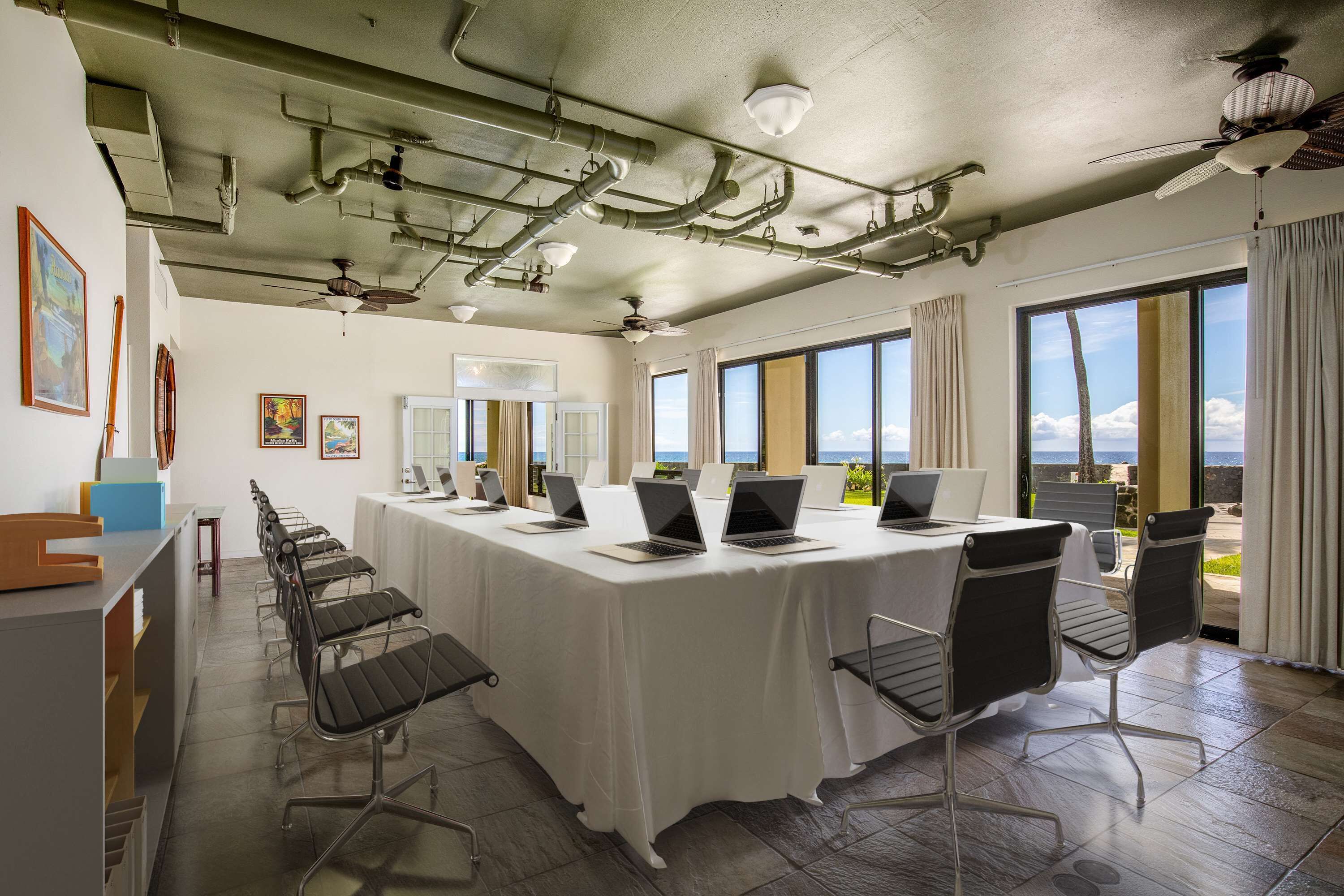 Una sala de conferencias con una larga mesa, varias computadoras portátiles y sillas.