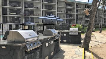 A multi-story hotel with balconies, outdoor seating, and a barbecue area with grills.