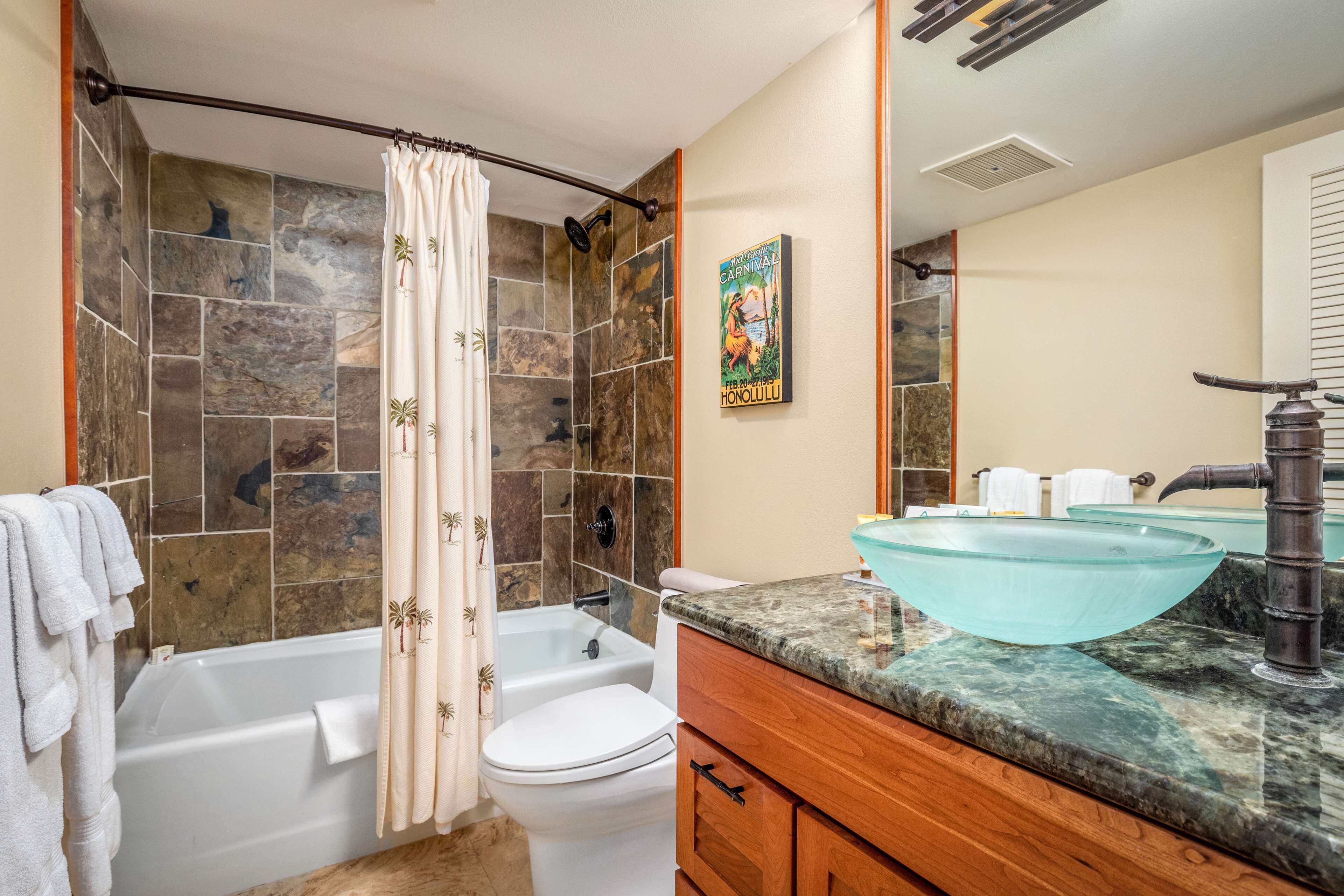 Une salle de bain avec une baignoire, des toilettes et un lavabo en verre.
