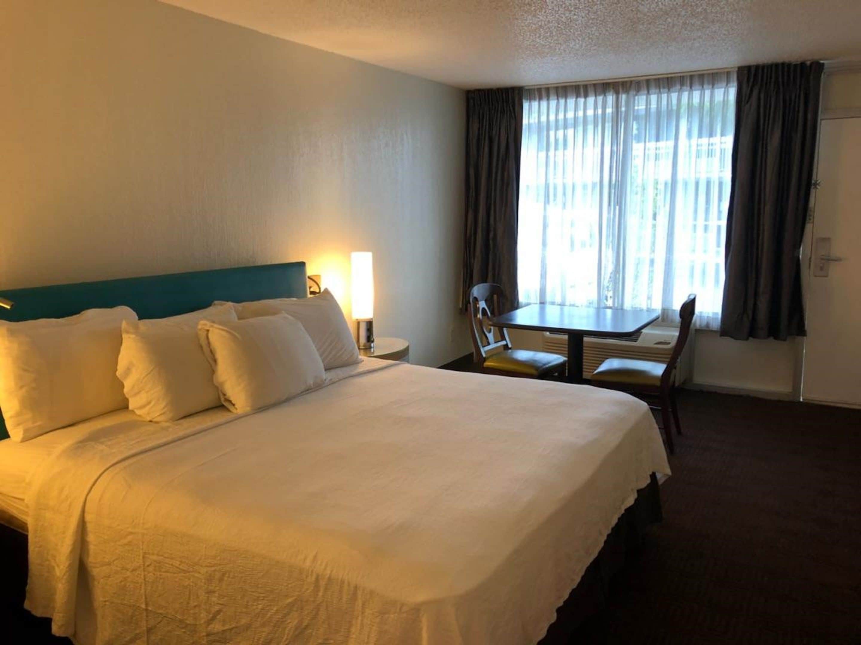 A hotel room with a large bed, a desk, and a chair.