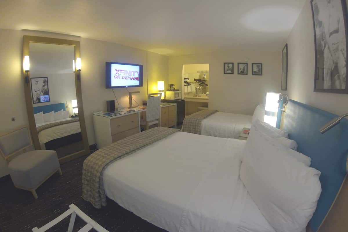 A hotel room with a bed, a desk, a chair, a TV, and a mirror.