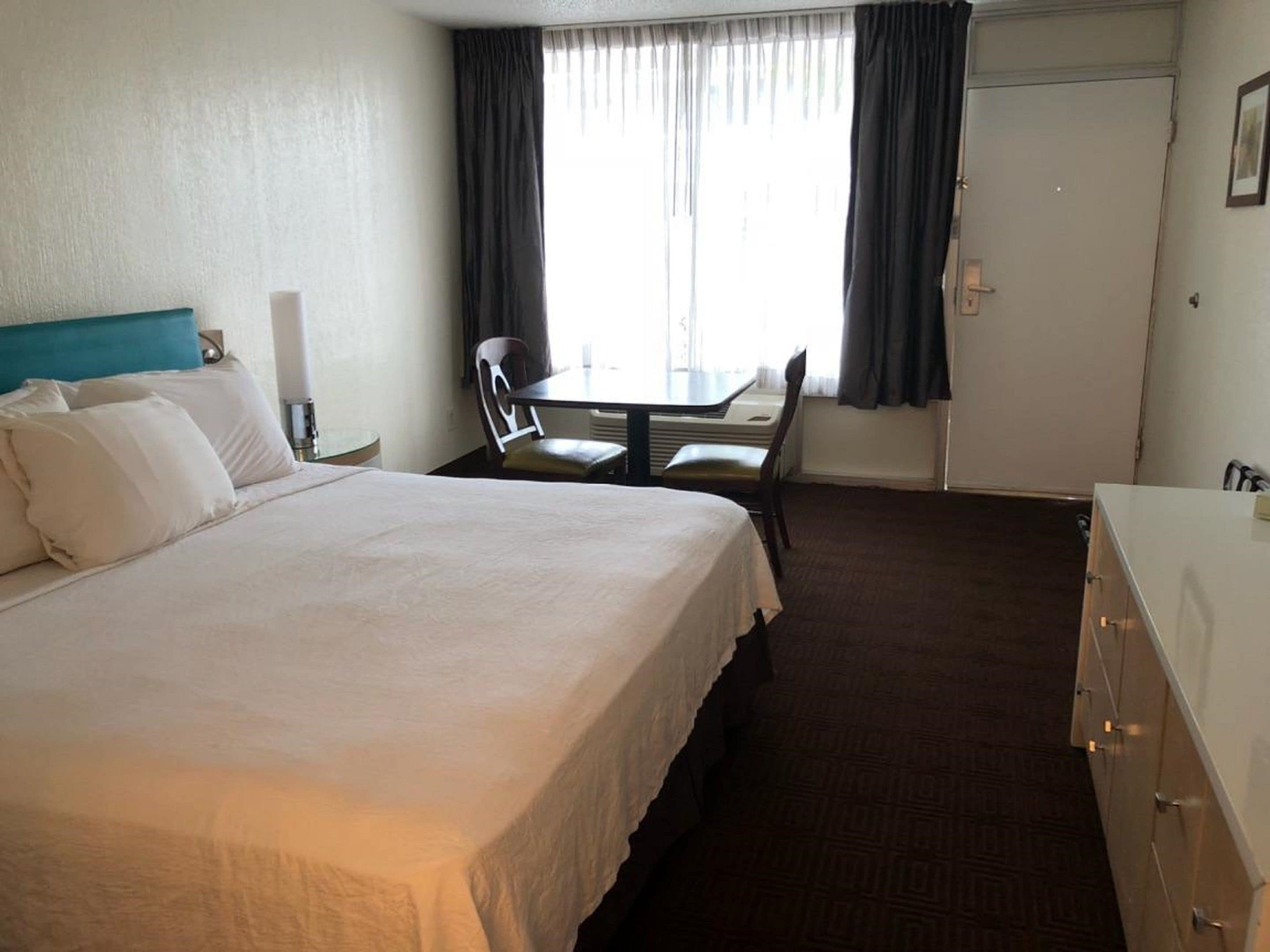 Una habitación de hotel con una cama grande, un escritorio, una silla y un aparador.