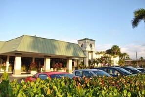 A hotel with a green roof, a clock tower, and a parking lot with several cars. - Floridian Hotel (Homestead)