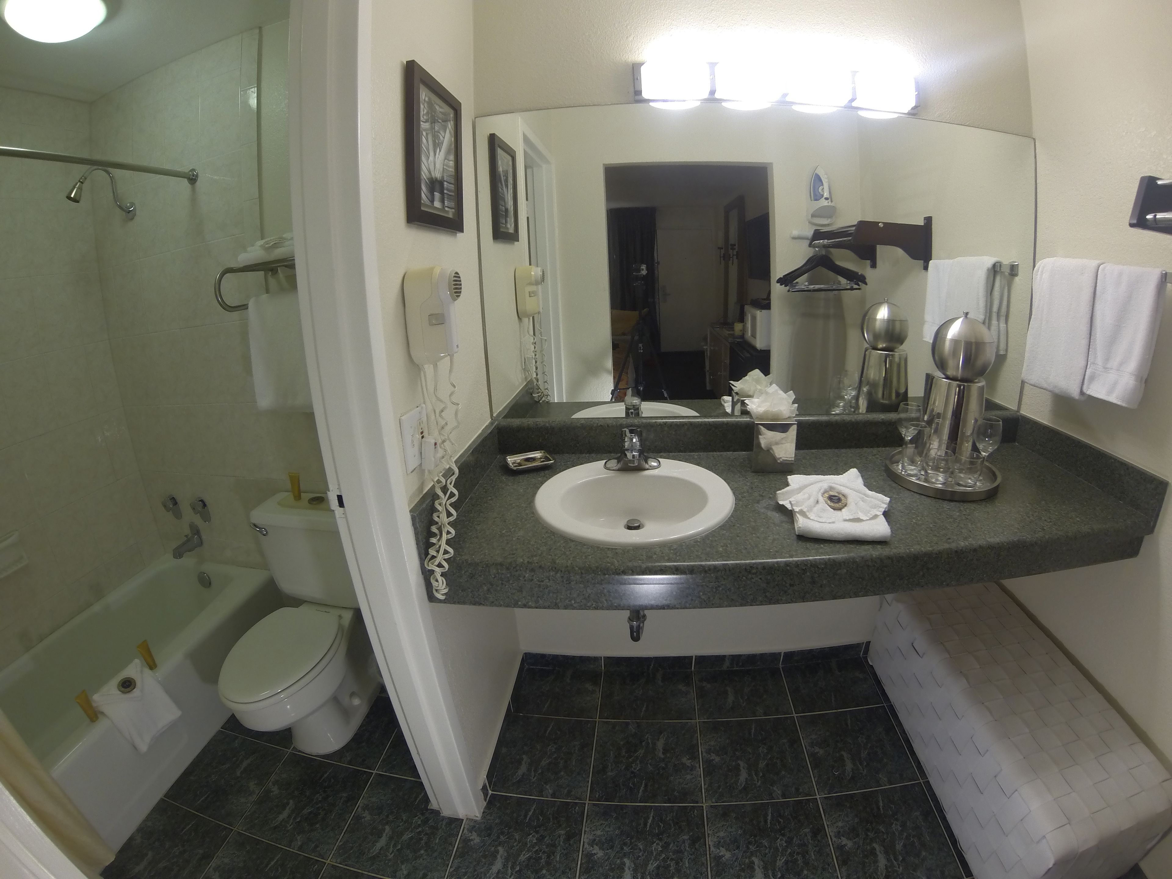 A bathroom with a sink, mirror, towel rack, and a shower area.