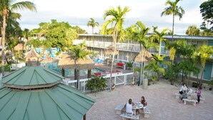 Et resort med swimmingpool, palmer og udendørs siddeområder.