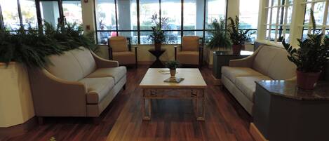 A lobby with leather sofas, a coffee table, and potted plants.