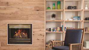 Een woonkamer met een open haard, een boekenkast en een gestreepte fauteuil.