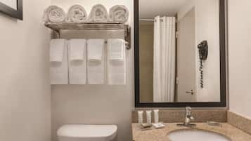 A bathroom with a toilet, a sink with a mirror, and a towel rack with neatly folded towels.