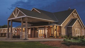 Een hotel met een overdekte ingang, stenen pilaren en een bord met 'Country Inn & Suites by Wyndham'.