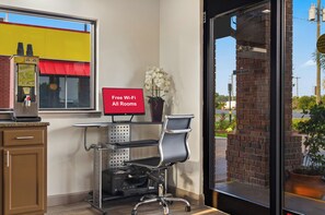 A hotel room with a desk, chair, and a computer monitor displaying 'Free Wi-Fi All Rooms'. - Red Roof Inn Baldwin (Jacksonville)