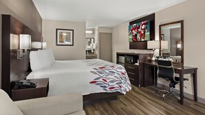 A hotel room with a large bed, a desk with a chair, a TV, and a mirror. - Red Roof Inn Baldwin (Jacksonville)