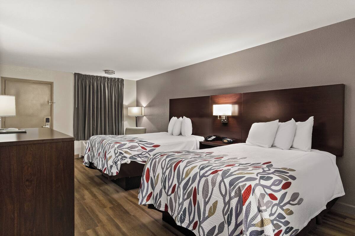 Habitación de hotel con dos camas, un escritorio y una silla.
