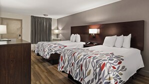 Una camera d'albergo con due letti, una scrivania e una sedia.
