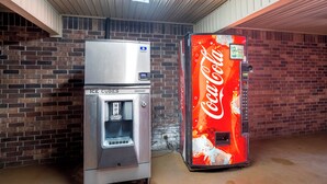 A vending machine and an ice dispenser in a room with brick walls and a sloped ceiling. - Red Roof Inn Baldwin (Jacksonville)