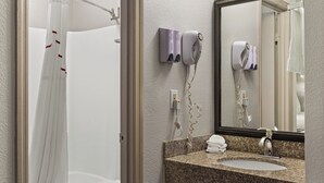 A bathroom with a shower curtain, a hairdryer, and a sink with a mirror. - Red Roof Inn Baldwin (Jacksonville)