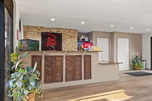 A reception desk with a Red Roof sign, a glass fish tank, and a potted plant. - Red Roof Inn Baldwin (Jacksonville)