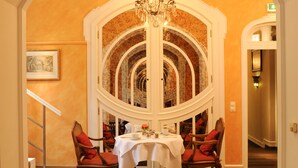 Un coin repas avec une table blanche, des chaises rouges et un lustre.