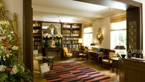 A well-lit library with bookshelves, a fireplace, and comfortable seating areas.