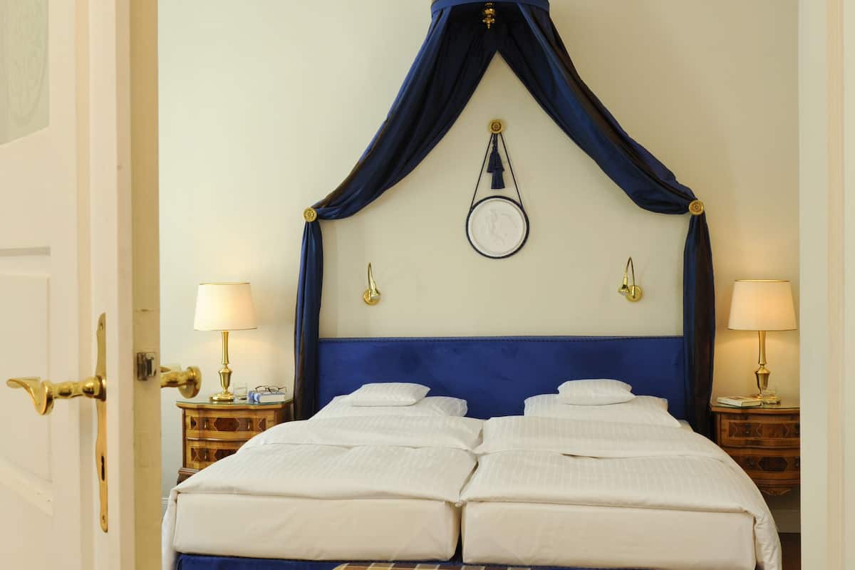 A bedroom with a large bed, a bench, two bedside tables, and a ceiling fan.