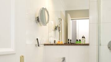 A bathroom with a white sink, a mirror, and a glass shower enclosure.