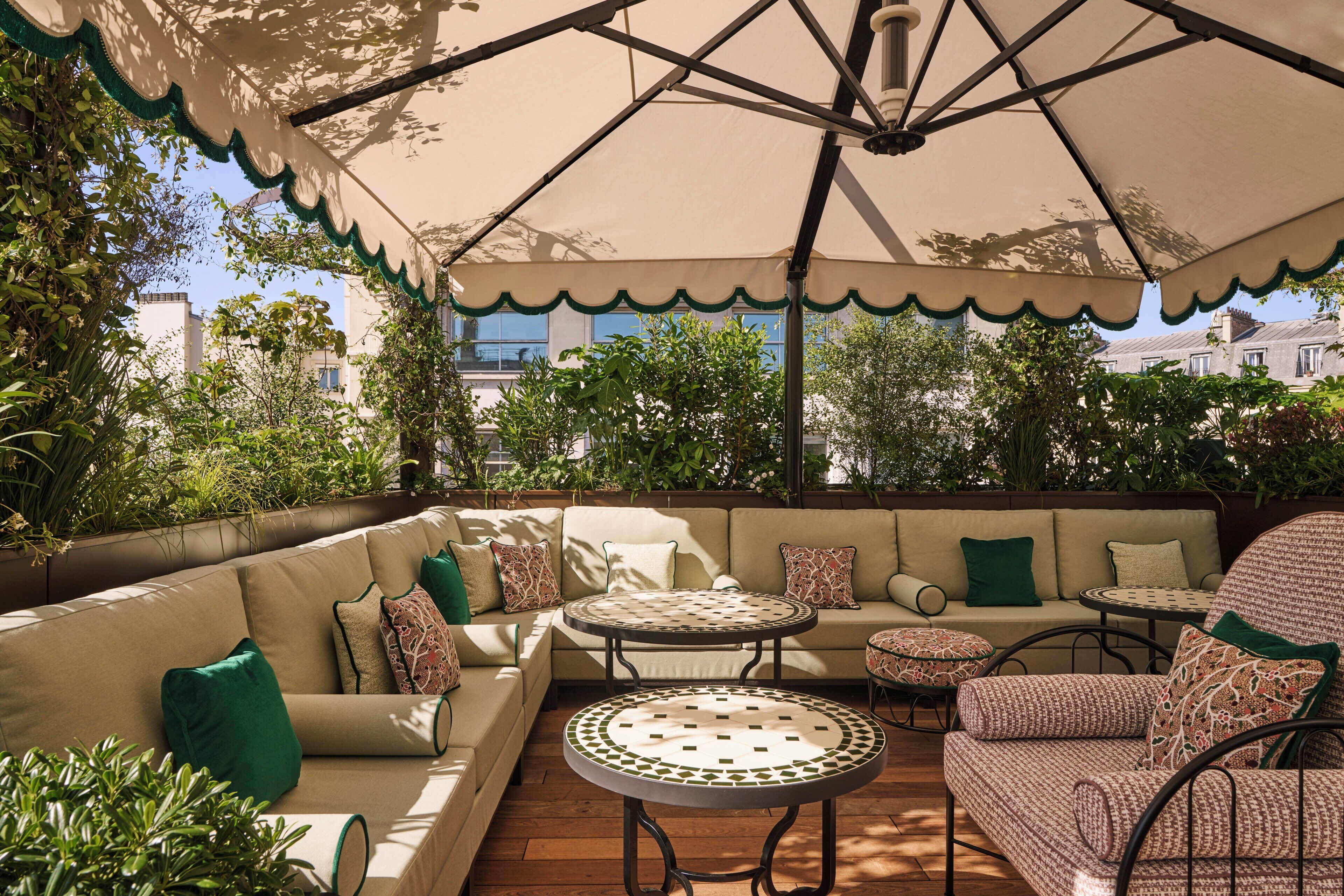An outdoor patio with a sofa, two round tables, and a patterned chair.