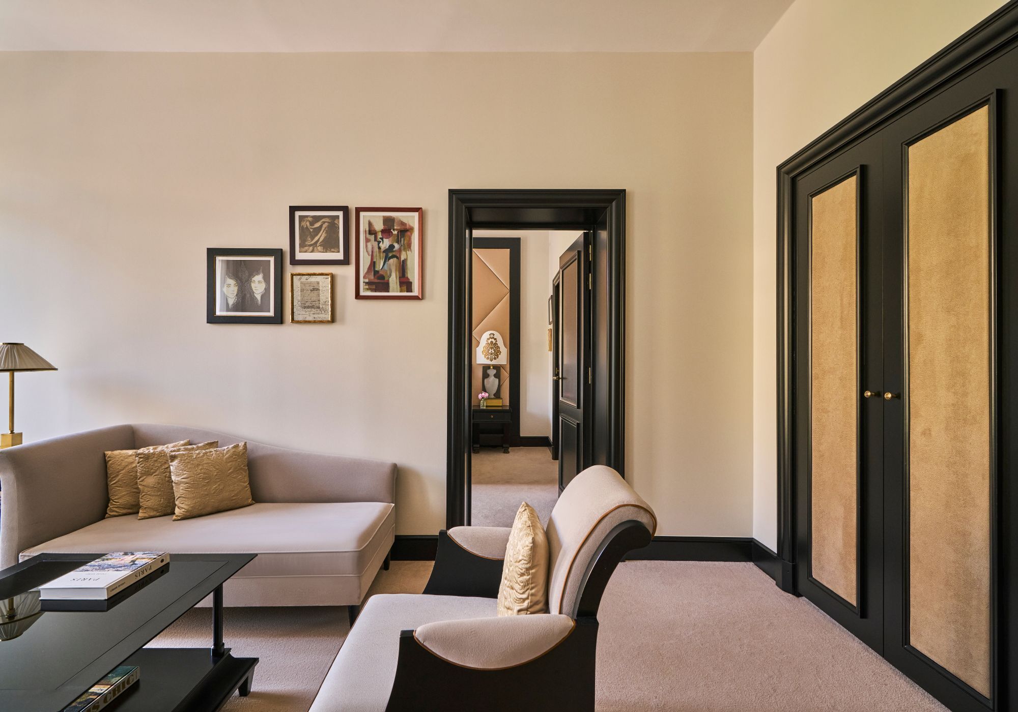 A modern living room with a sofa, armchairs, a coffee table, and framed artwork on the wall.