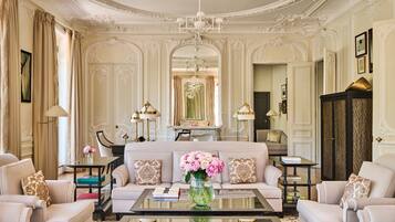 A luxurious living room with a sofa, armchairs, a coffee table, and decorative elements like flowers and lamps.
