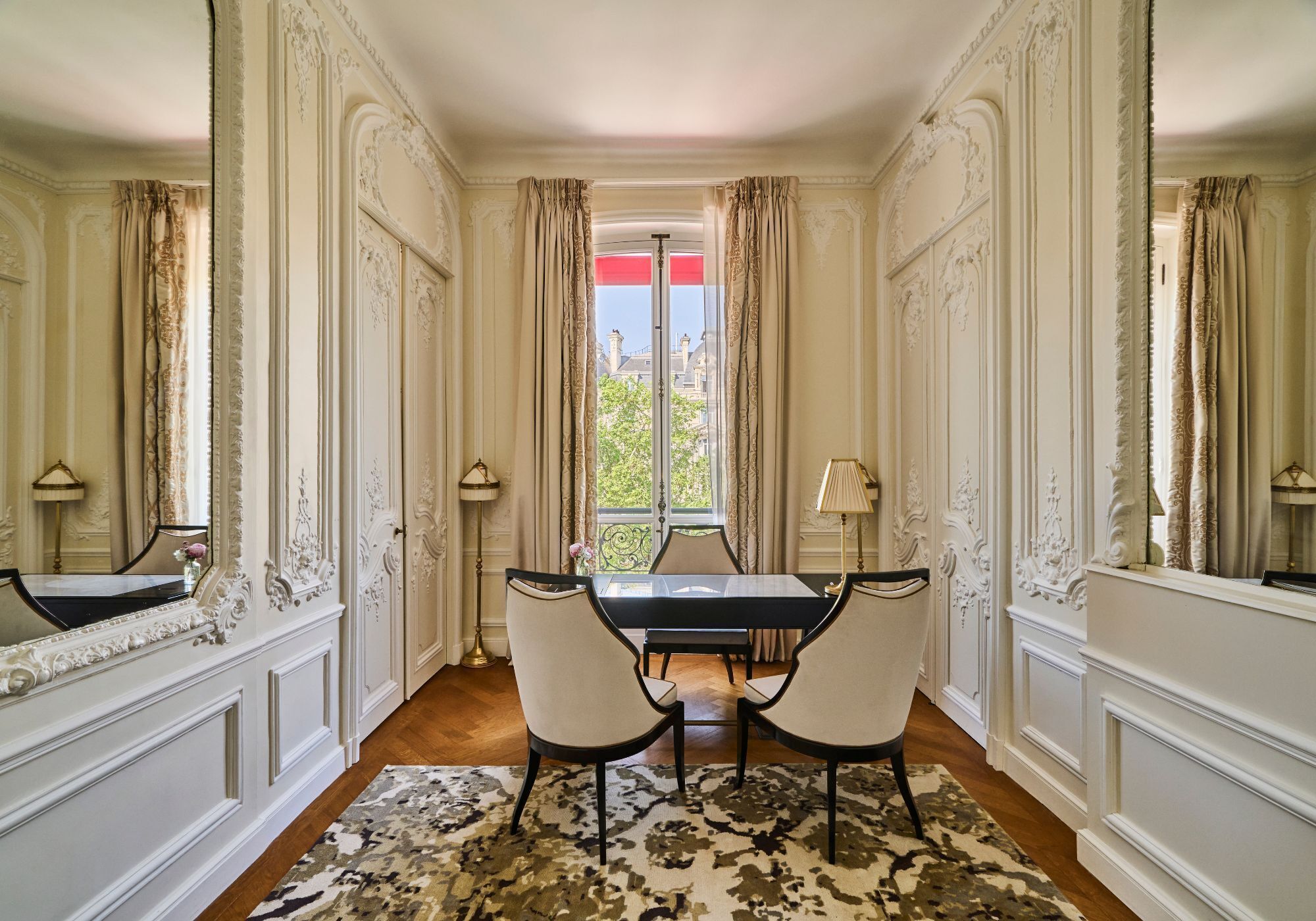 A dining room with a table and chairs, a patterned rug, and ornate wall decorations.