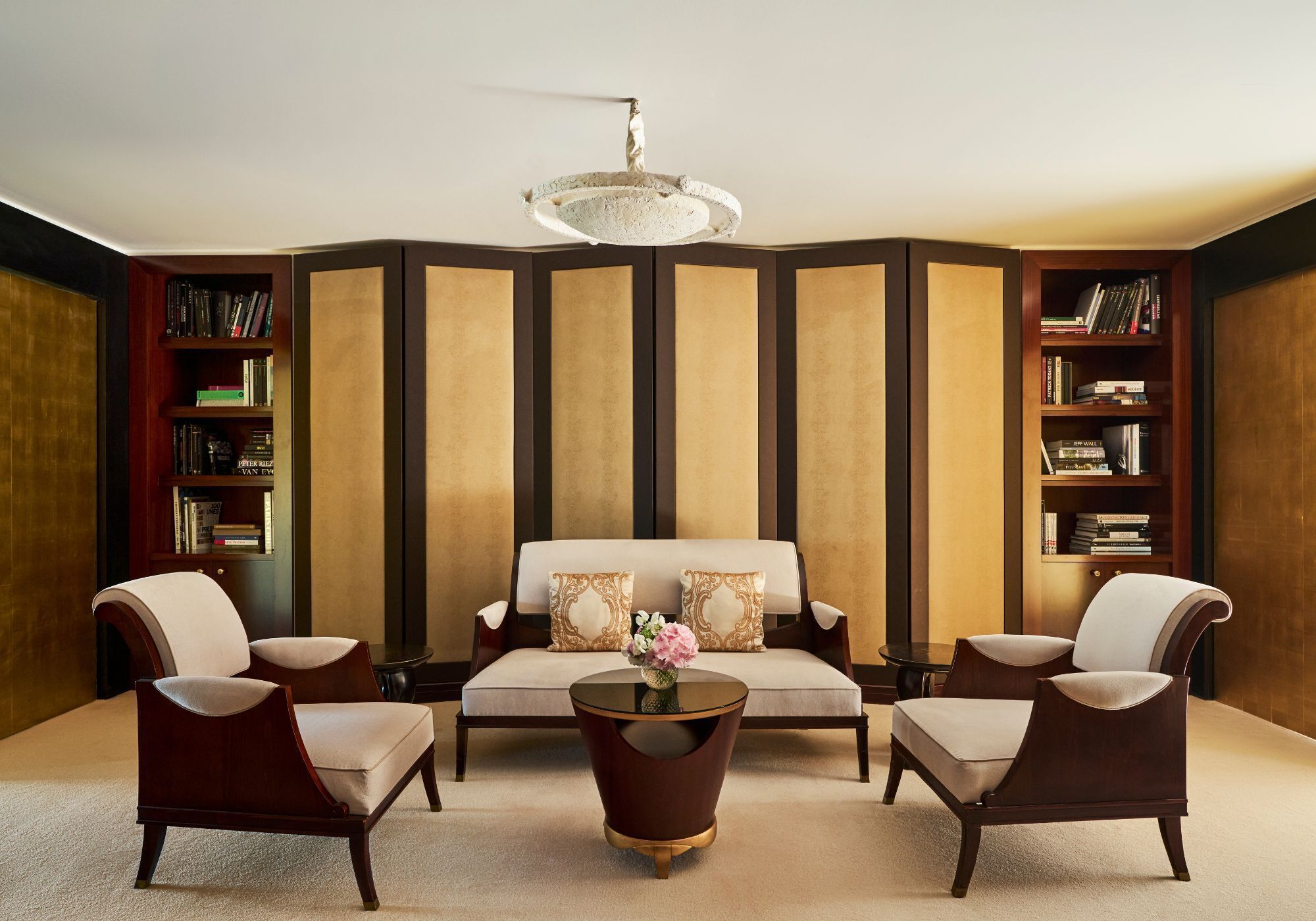 A room with a sofa, two armchairs, a coffee table, and bookshelves.