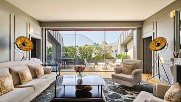A modern living room with a sofa, armchairs, a coffee table, and a large window with a view of the outside.