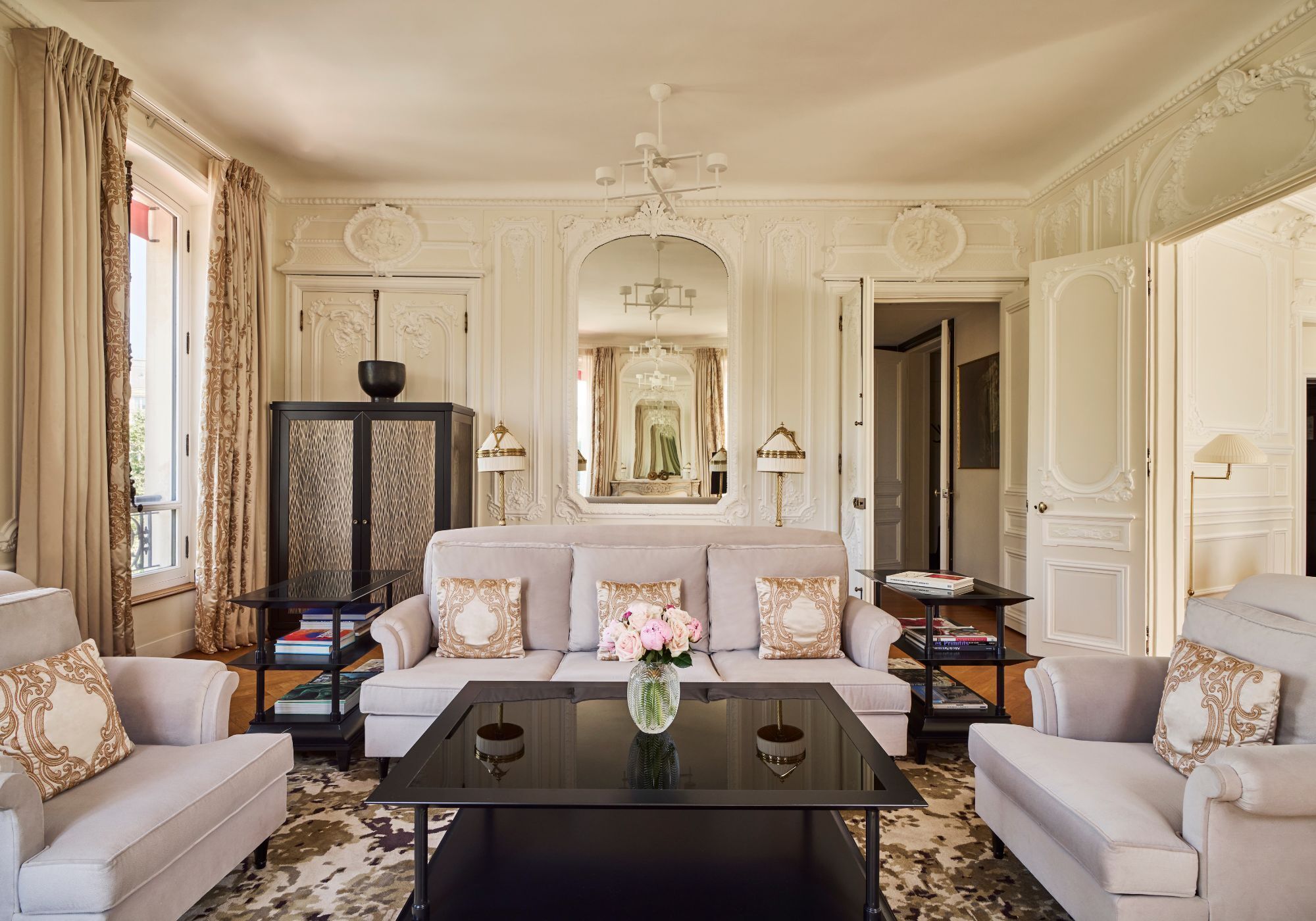 Una sala de estar lujosa con sofá, sillones, una mesa de centro y un espejo decorativo.
