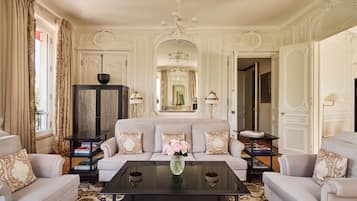 Una sala de estar lujosa con sofá, sillones, una mesa de centro y un espejo decorativo.